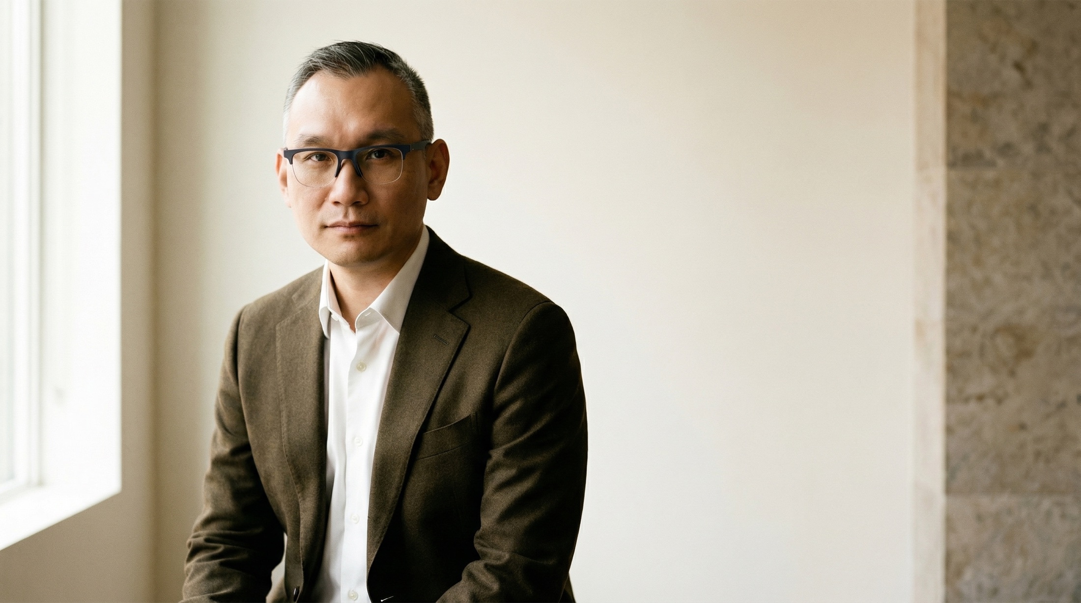 Editorial portrait of Erwin Choo seated in natural window light.